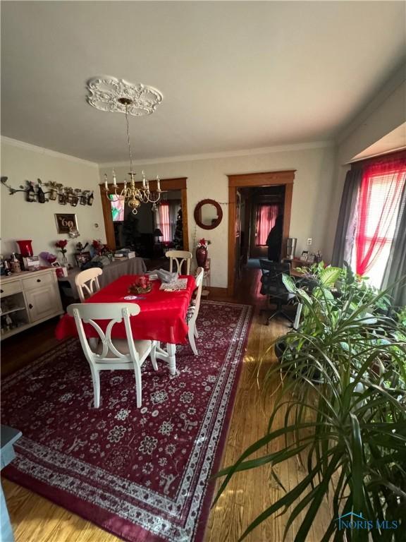 dining room featuring hardwood / wood-style flooring, ornamental molding, and a notable chandelier