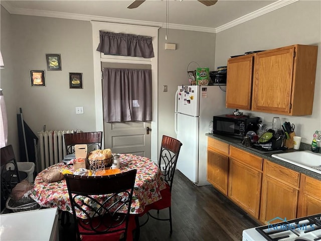 dining space with ceiling fan, dark hardwood / wood-style flooring, ornamental molding, and sink