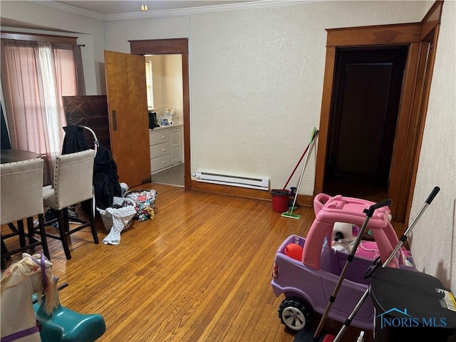 interior space featuring hardwood / wood-style flooring, ornamental molding, and a baseboard radiator