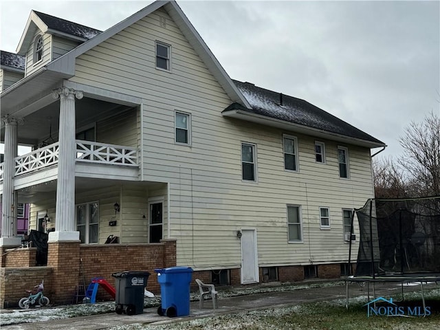 rear view of house featuring a trampoline and a balcony