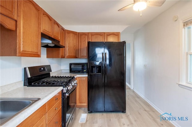 kitchen with black appliances, ceiling fan, sink, and light hardwood / wood-style flooring