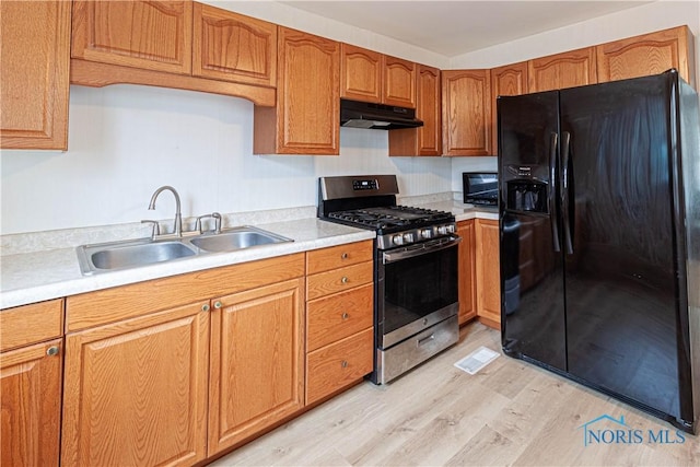 kitchen featuring gas range, black refrigerator with ice dispenser, sink, and light hardwood / wood-style floors