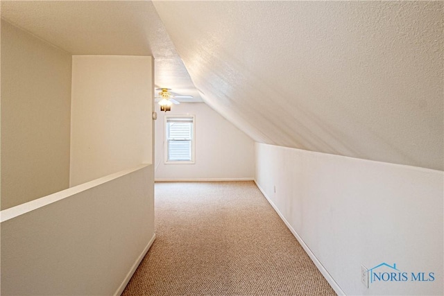 additional living space featuring a textured ceiling, ceiling fan, light carpet, and vaulted ceiling