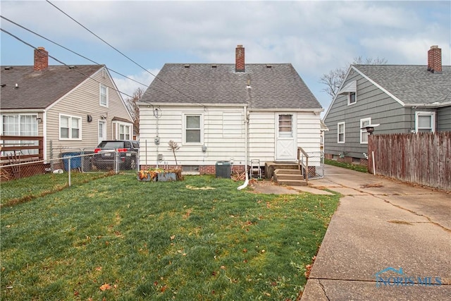 rear view of property featuring central air condition unit and a yard