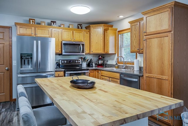 kitchen with wood counters, a kitchen breakfast bar, sink, appliances with stainless steel finishes, and tasteful backsplash