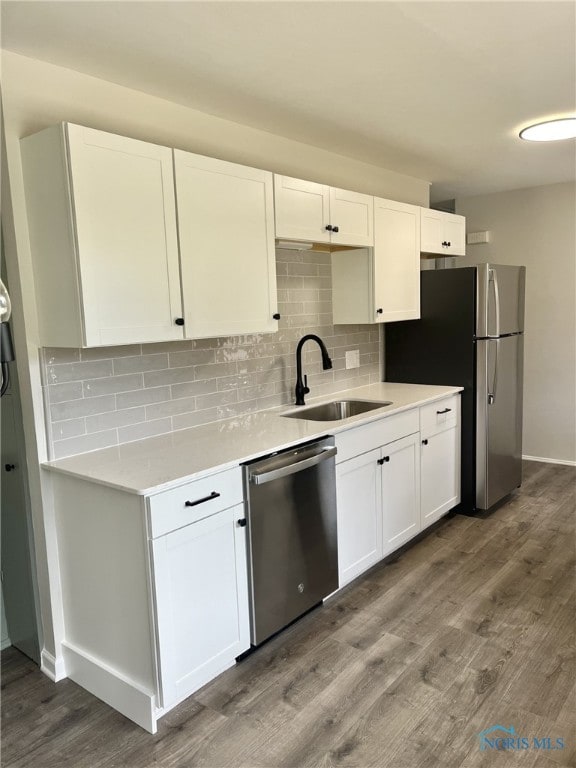 kitchen with hardwood / wood-style floors, appliances with stainless steel finishes, white cabinetry, and sink