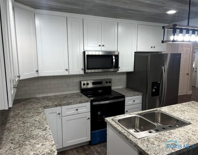 kitchen featuring white cabinetry, tasteful backsplash, light stone counters, hanging light fixtures, and stainless steel appliances