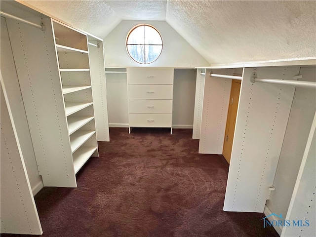 spacious closet featuring dark carpet and lofted ceiling