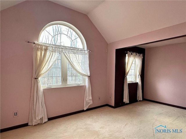 carpeted spare room featuring lofted ceiling