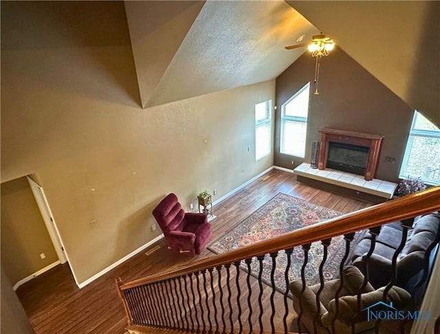 additional living space featuring a textured ceiling, ceiling fan, dark hardwood / wood-style floors, lofted ceiling, and a tiled fireplace