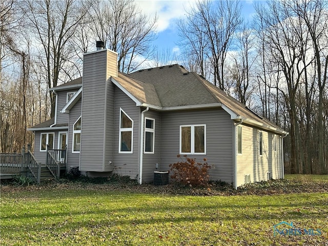 rear view of property featuring a lawn, a wooden deck, and central AC unit