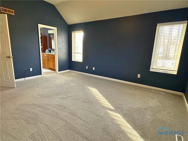 carpeted spare room featuring lofted ceiling and a healthy amount of sunlight