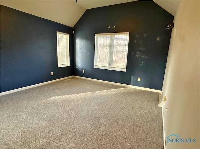 spare room featuring carpet floors and vaulted ceiling