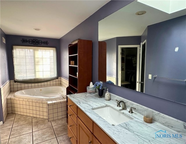 bathroom featuring tile patterned flooring, vanity, and tiled bath