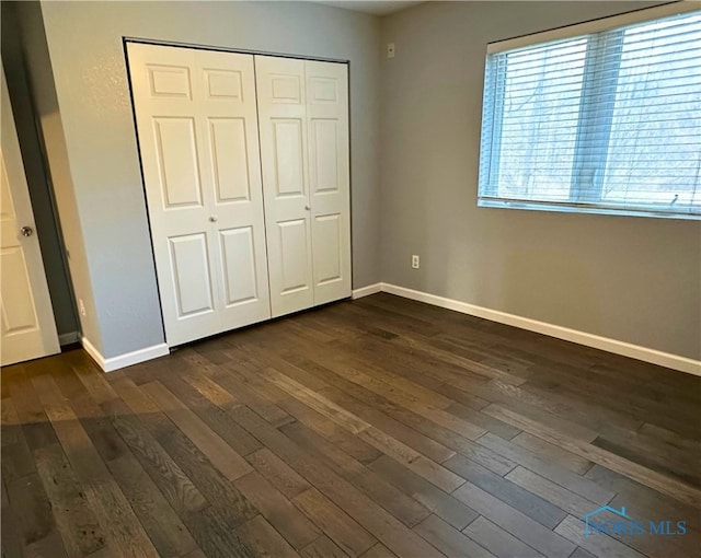 unfurnished bedroom featuring dark hardwood / wood-style flooring and a closet