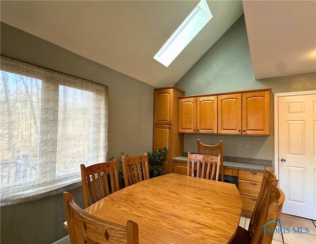 dining area with lofted ceiling with skylight, light tile patterned floors, and built in desk