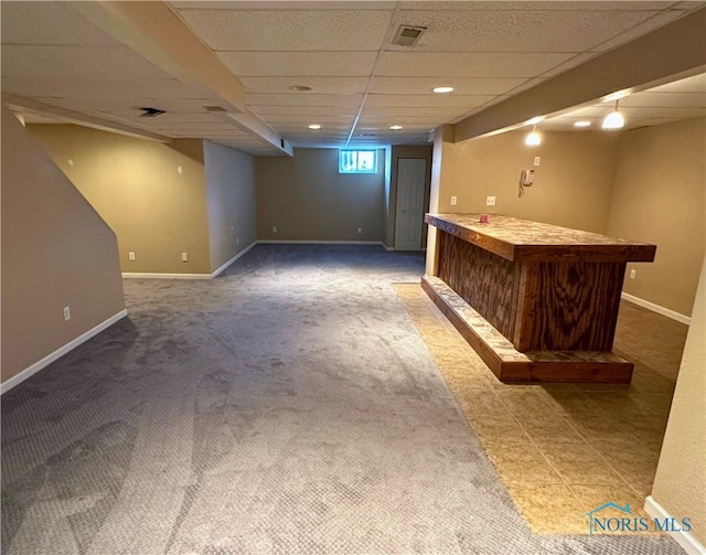 basement featuring a paneled ceiling and carpet floors