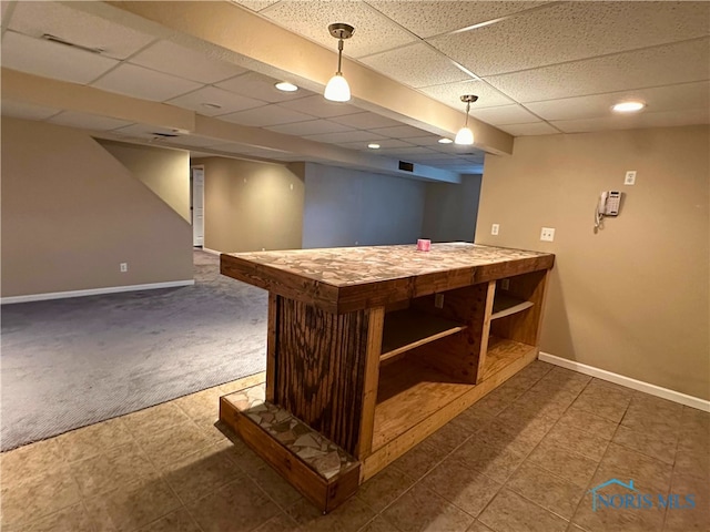 bar with a drop ceiling, decorative light fixtures, and dark colored carpet