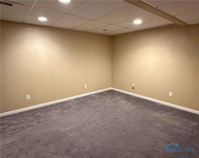 unfurnished room with dark colored carpet and a paneled ceiling