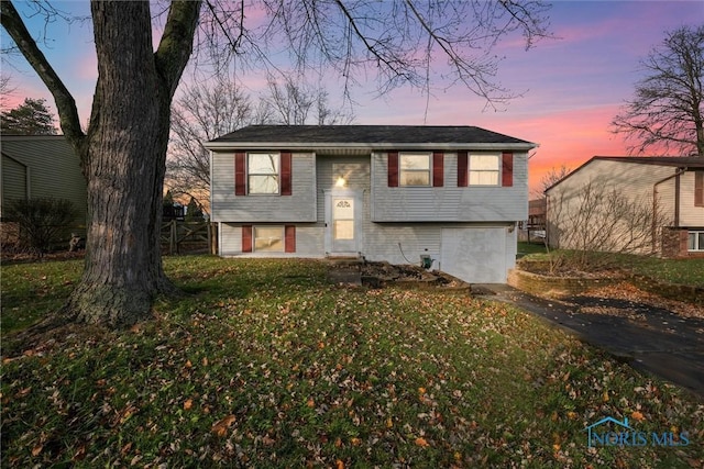 split foyer home featuring a yard and a garage