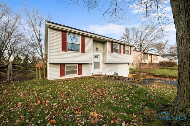 raised ranch featuring a garage and a front lawn