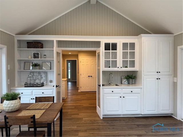 kitchen featuring dark hardwood / wood-style floors, white cabinetry, lofted ceiling, and ornamental molding