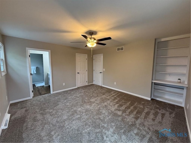 unfurnished bedroom featuring dark colored carpet, ensuite bath, and ceiling fan