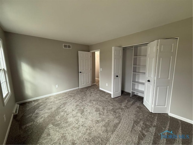 unfurnished bedroom featuring dark carpet and a closet