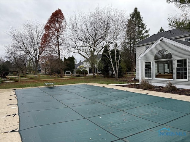 view of pool featuring a lawn and a diving board