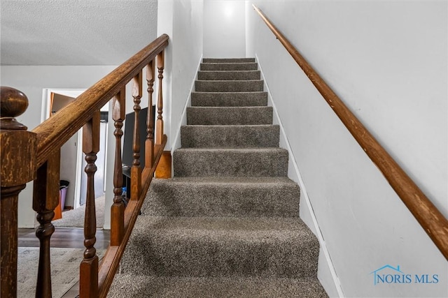 stairs featuring hardwood / wood-style floors and a textured ceiling