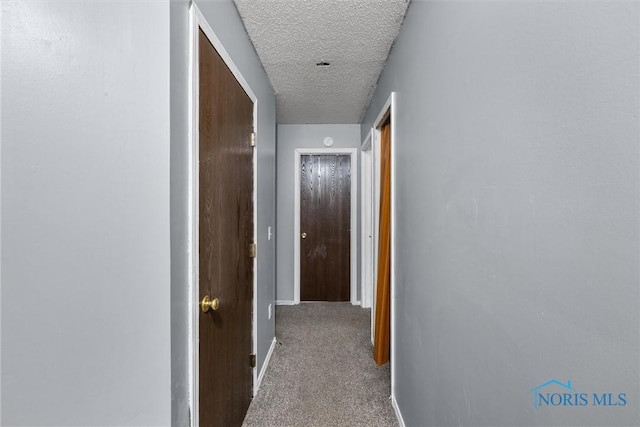 corridor with carpet and a textured ceiling