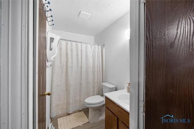 bathroom featuring vanity, wood-type flooring, a textured ceiling, and toilet