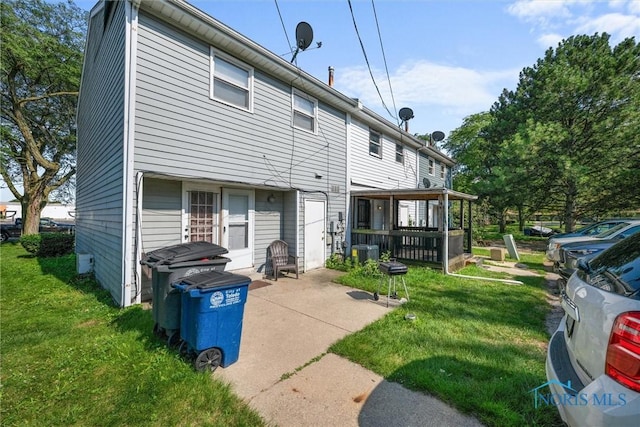 rear view of property featuring a lawn and cooling unit