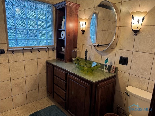 bathroom featuring tile patterned flooring, vanity, toilet, and tile walls