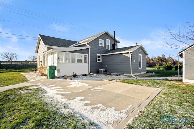 back of property with a lawn, a sunroom, cooling unit, and a patio