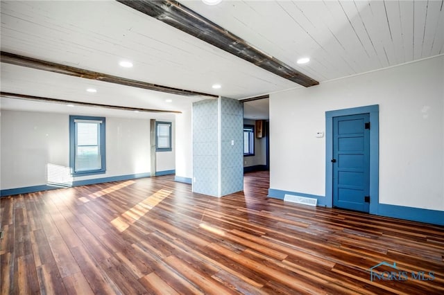 spare room featuring beamed ceiling and dark hardwood / wood-style floors