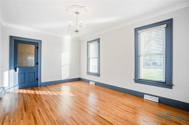 spare room featuring hardwood / wood-style floors and an inviting chandelier