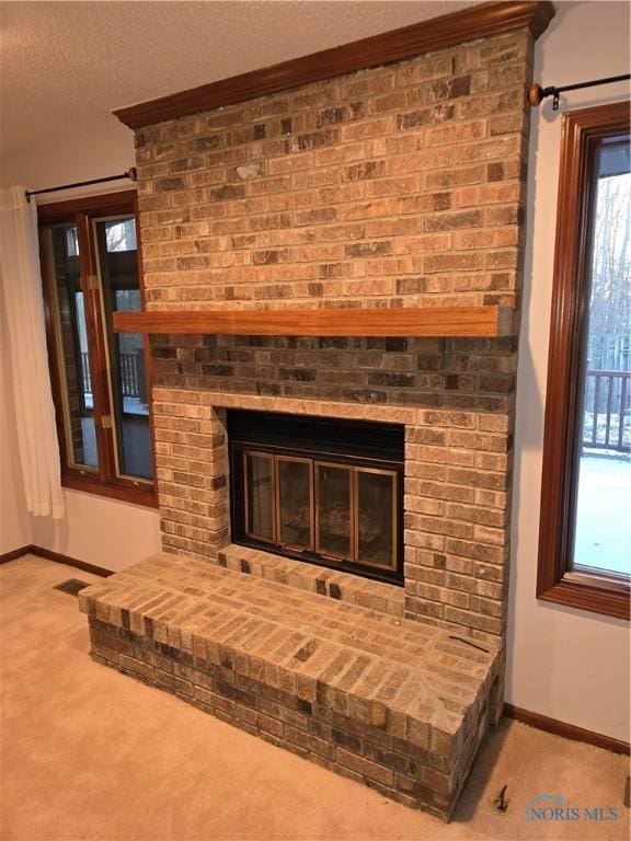 interior details with carpet flooring, a textured ceiling, and a brick fireplace