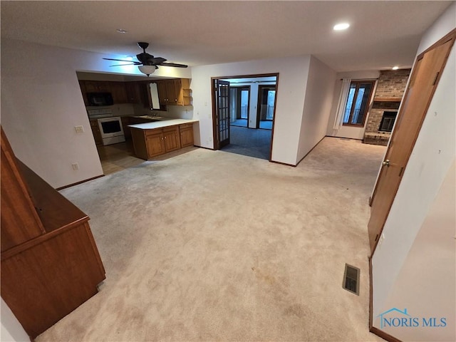 carpeted living room with ceiling fan, sink, and a brick fireplace