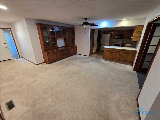 unfurnished living room featuring light carpet, a textured ceiling, and ceiling fan