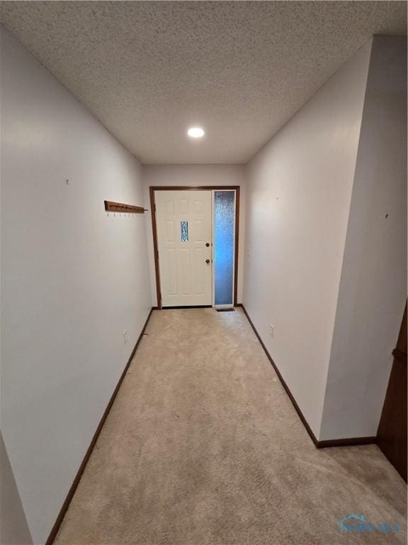 doorway with light carpet and a textured ceiling