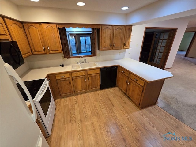 kitchen featuring kitchen peninsula, sink, light colored carpet, and black appliances