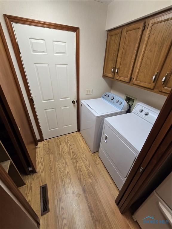 clothes washing area featuring cabinets, independent washer and dryer, and light hardwood / wood-style floors