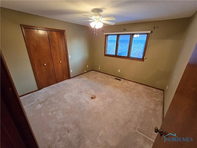 unfurnished bedroom with carpet floors, a closet, and ceiling fan