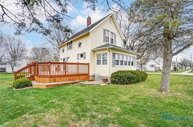 back of house featuring a lawn and a wooden deck