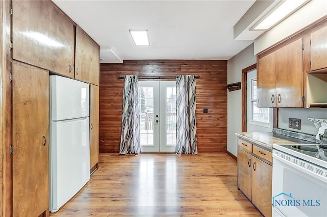 kitchen with light hardwood / wood-style floors, white appliances, wooden walls, and french doors