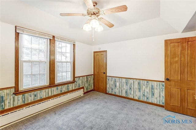 spare room with light carpet, a tray ceiling, baseboard heating, and ceiling fan