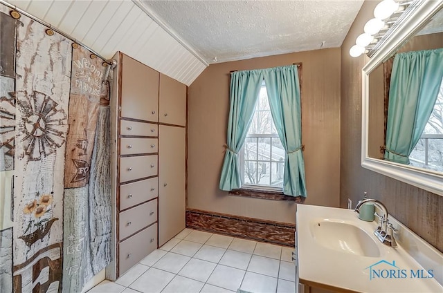 bathroom with tile patterned floors, vanity, vaulted ceiling, and a textured ceiling