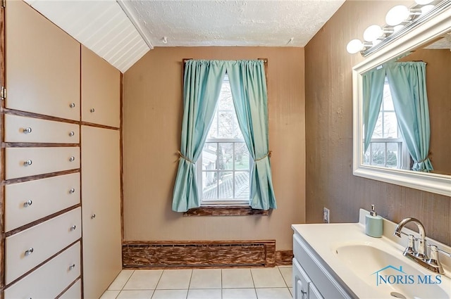 bathroom with tile patterned floors, vanity, a textured ceiling, and vaulted ceiling