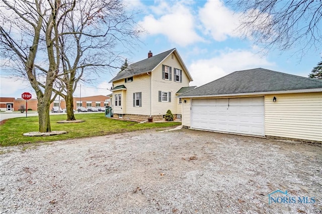 view of front facade featuring a front yard, a garage, and an outdoor structure